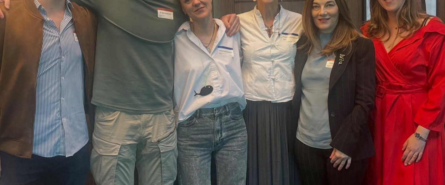 Six people standing together in a line in a conference-centre lobby